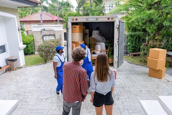 A moving team loading boxes and household items into a truck at a home